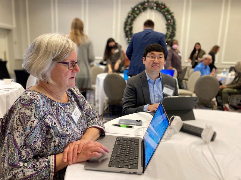 Diane Horm and Wonkyung Jang sit at round table in large conference room