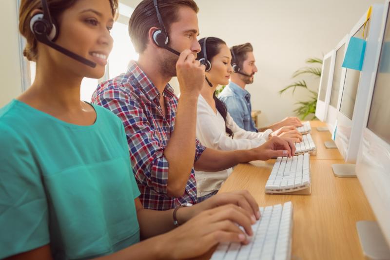 Business team working together at a call center wearing headsets