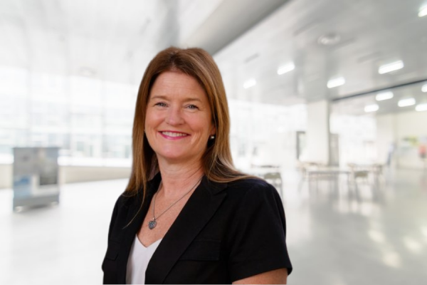 Woman with shoulder length brown hair in black top stands in open meeting room; Doroty Espelage