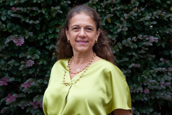 ayse belger; woman in chartreuse blouse stands in front of burgundy foiliage outside