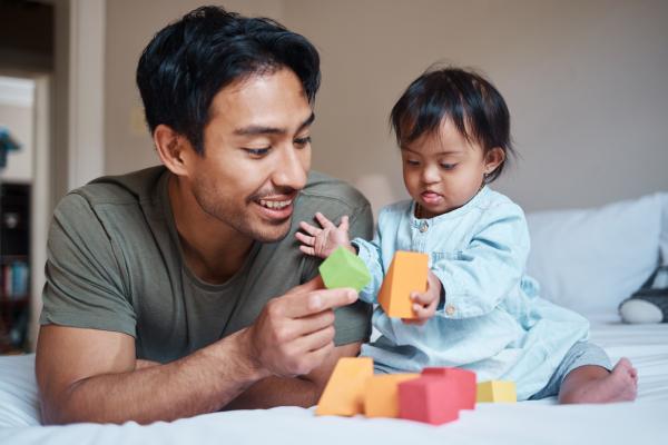 father and his baby with down syndrome play with educational blocks