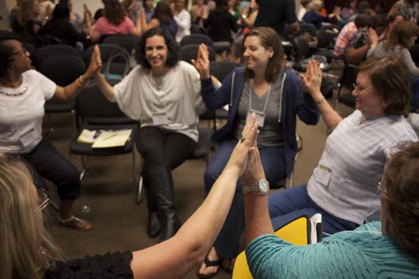 Adults sitting in a circle with hands joined together