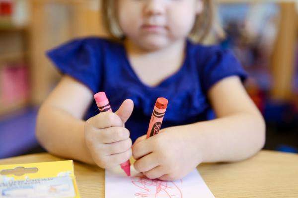 Young girl drawing with crayons