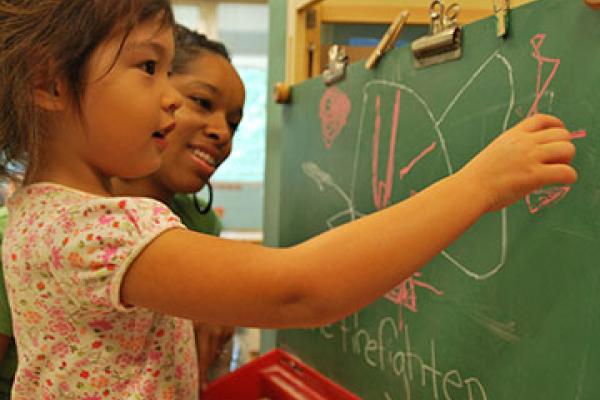 Adult with young child at a chalkboard