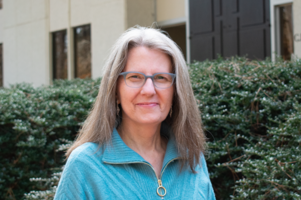 Gisele Crawford; woman with should length light brown and gray hair and glasses smiles at camera
