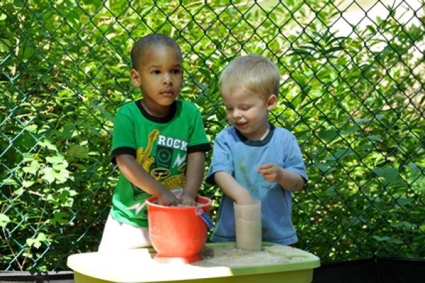 Two boys playing with a sand bucket