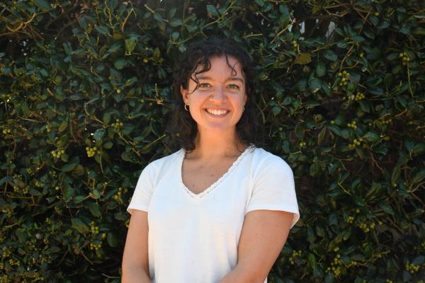 Julia Mackessy stands outside in front of leafy hedge