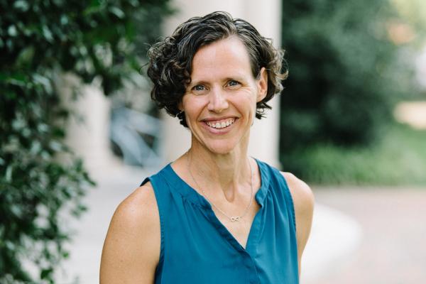 Headshot photo of Kara Hume standing on UNC campus wearing a sleeveless teal blouse