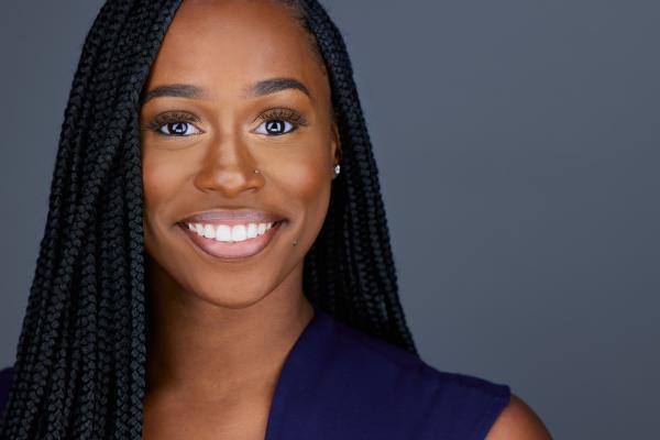Jamilah Silver headshot style photo; woman with long black hair smiles at camera