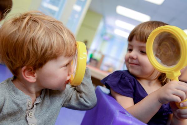 Two young children with magnifying glasses