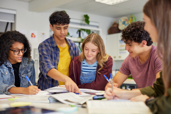 five young teens working together at classroom table