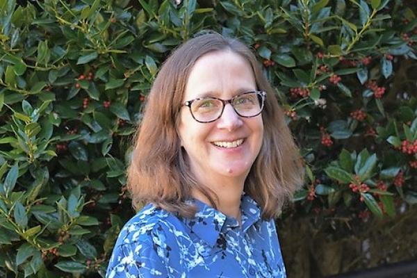 Noreen Yazejian; woman with shoulder length light brown hair and glasses smiles at camera