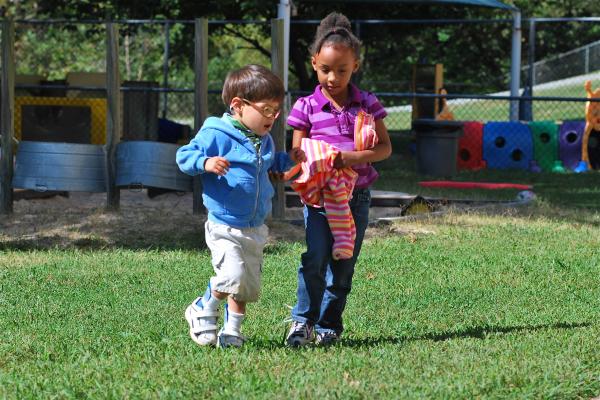 Two young children walking across playground