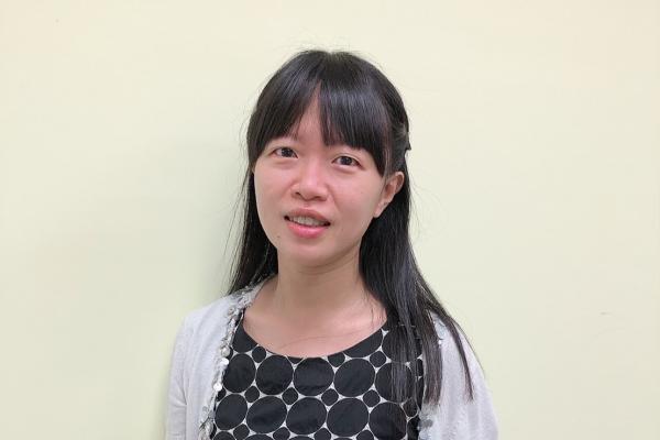 Szu-Yin Chu; woman with long dark hair and bangs wearing a geometric design dress and cardigan smiles at camera