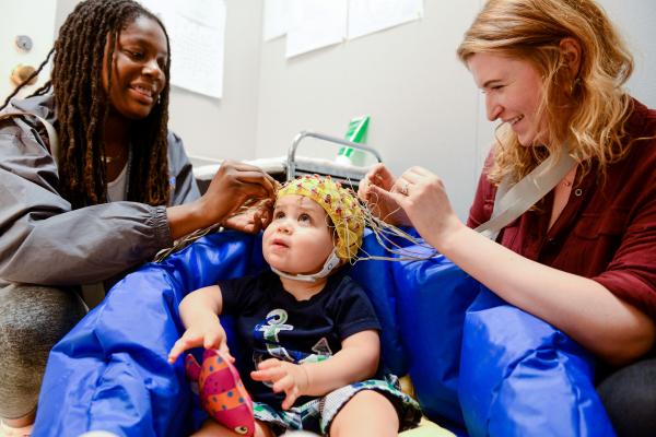 Two researchers putting sensors on a toddler