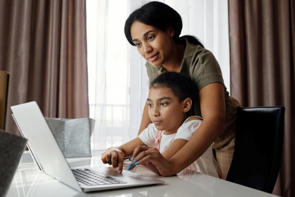 Adult helping a child to use a laptop computer