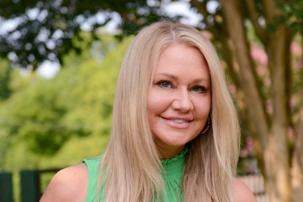 sherri britt williams; woman with long blond hair and wearing a bright green top smiles at camera