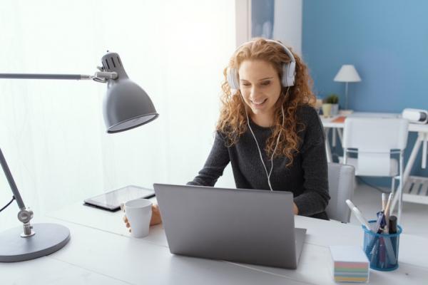 red haired woman wearing headphones working at desk