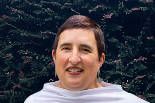 Allison De Marco; woman with short brown hair and wearing a white cowl smiles at camera