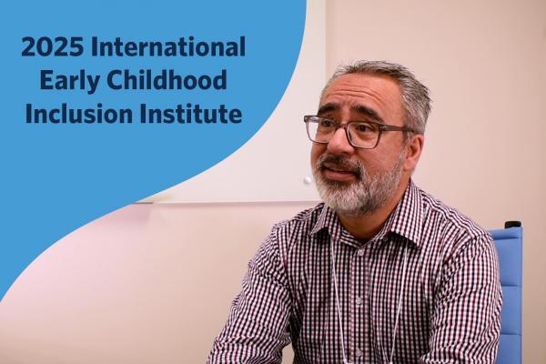 Sam Atencio sitting in a chair at a table speaking to an interviewer out of frame. Image contains text: "2025 International Early Childhood Inclusion Institute."