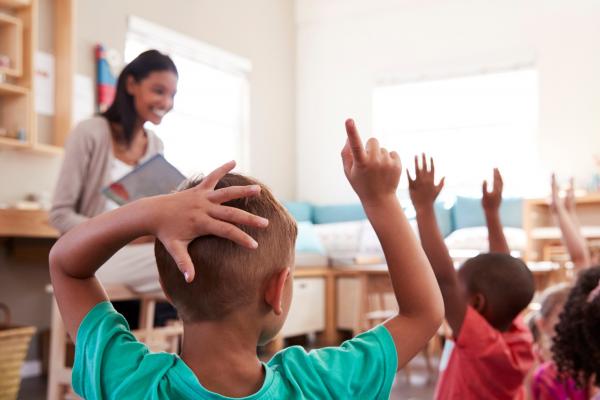 pre-k pupils raising hands to answer question from teacher 