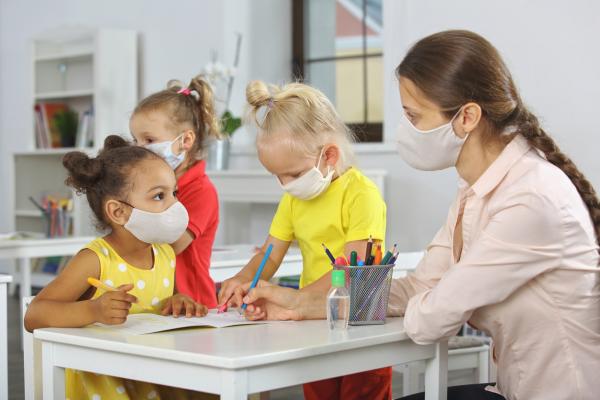 young children in classroom with teacher; all wear masks for COVID protocol