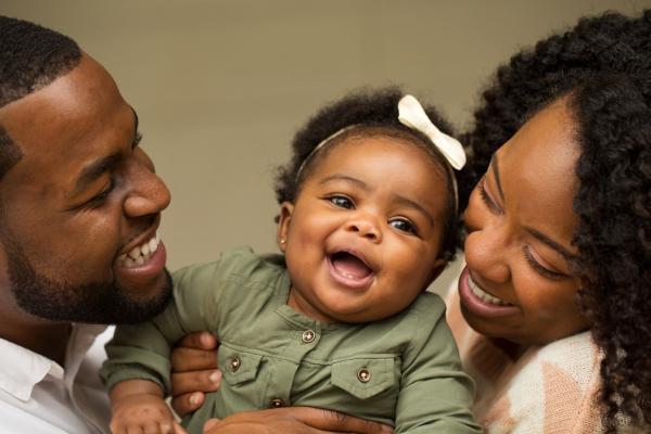 happy Black family, dad, mom, and little girl, smiling at camera
