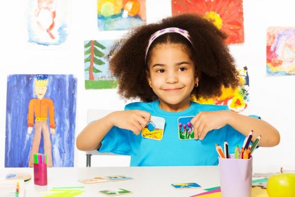 young girl with curly dark hair sitting at table in school working on project