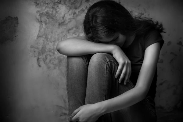 black and white photo of teen girl slumping against wall