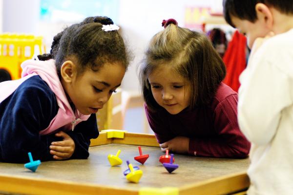 Two young children looking at spinning tops