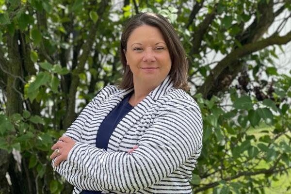 rebekah hornak; woman in black and white striped blazer stands in front of large green shrubbery