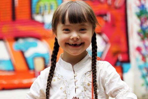 Young girl smiling in front of a brightly colored background