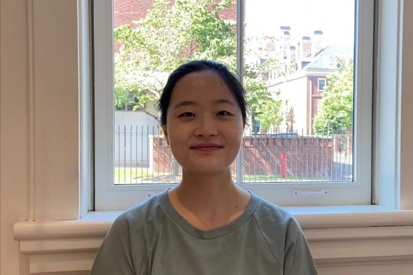 iris kang; woman in pale green t-shirt sits in front of big window