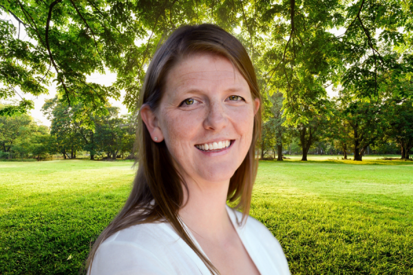 Headshot of Jessica Steinbrenner standing outside in sunshine with greenery behind her 