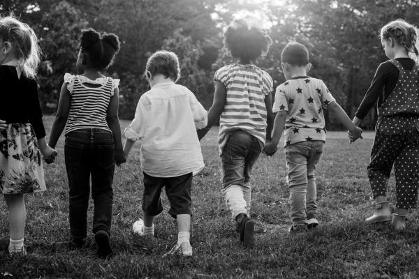 black and white photo of a group of kindergarten kids friends holding hands playing at park