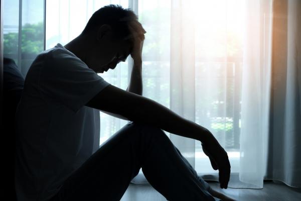 shadowy man sitting in the corner of the room; concept depicts depression or stress 