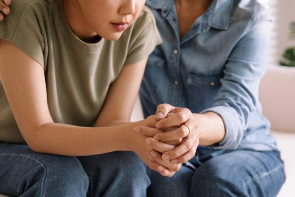 mom holding hands of teen, showing trust, comfort, help during life crisis/stressful time 