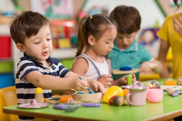 pre-k classroom of children playing at table with small toys