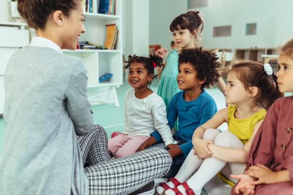 Teacher is playing with cheerful children at kindergarten