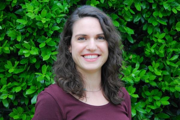 Rebecca Roppolo stands in front of a leafy shrub