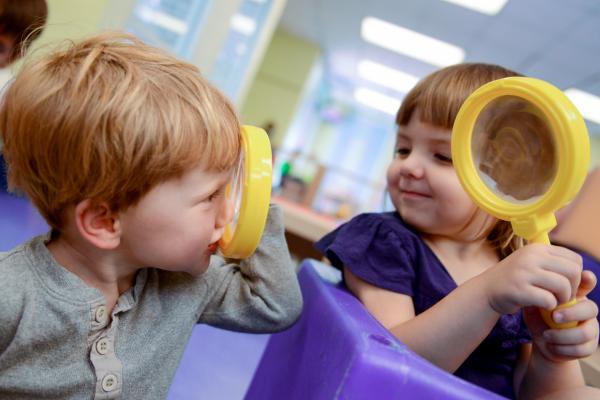 Two young children holding magnifying glasses