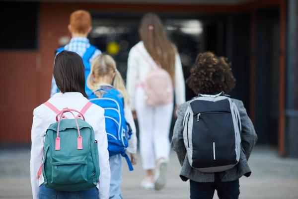 Rear view of five students with backpacks going to school for classes