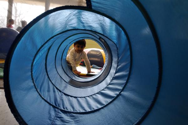 Young child peeking through play tunnel