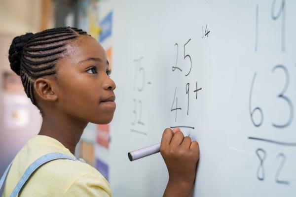 School child thinking while doing mathematics problem.