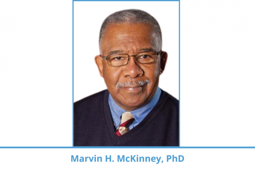 Marvin H. McKinney; man with graying hair wears navy sweater vest, medium blue shirt, and colorful tie